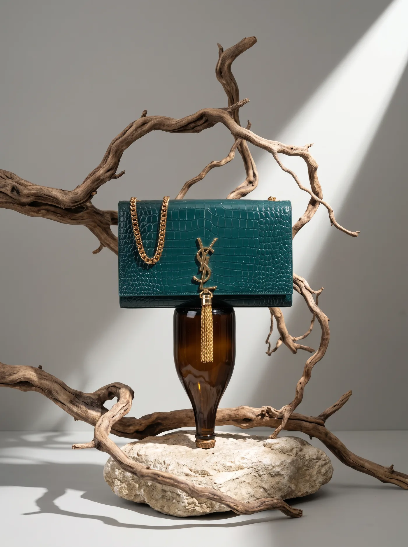 Structured flap bag with a chain strap on an amber glass bottle amid driftwood