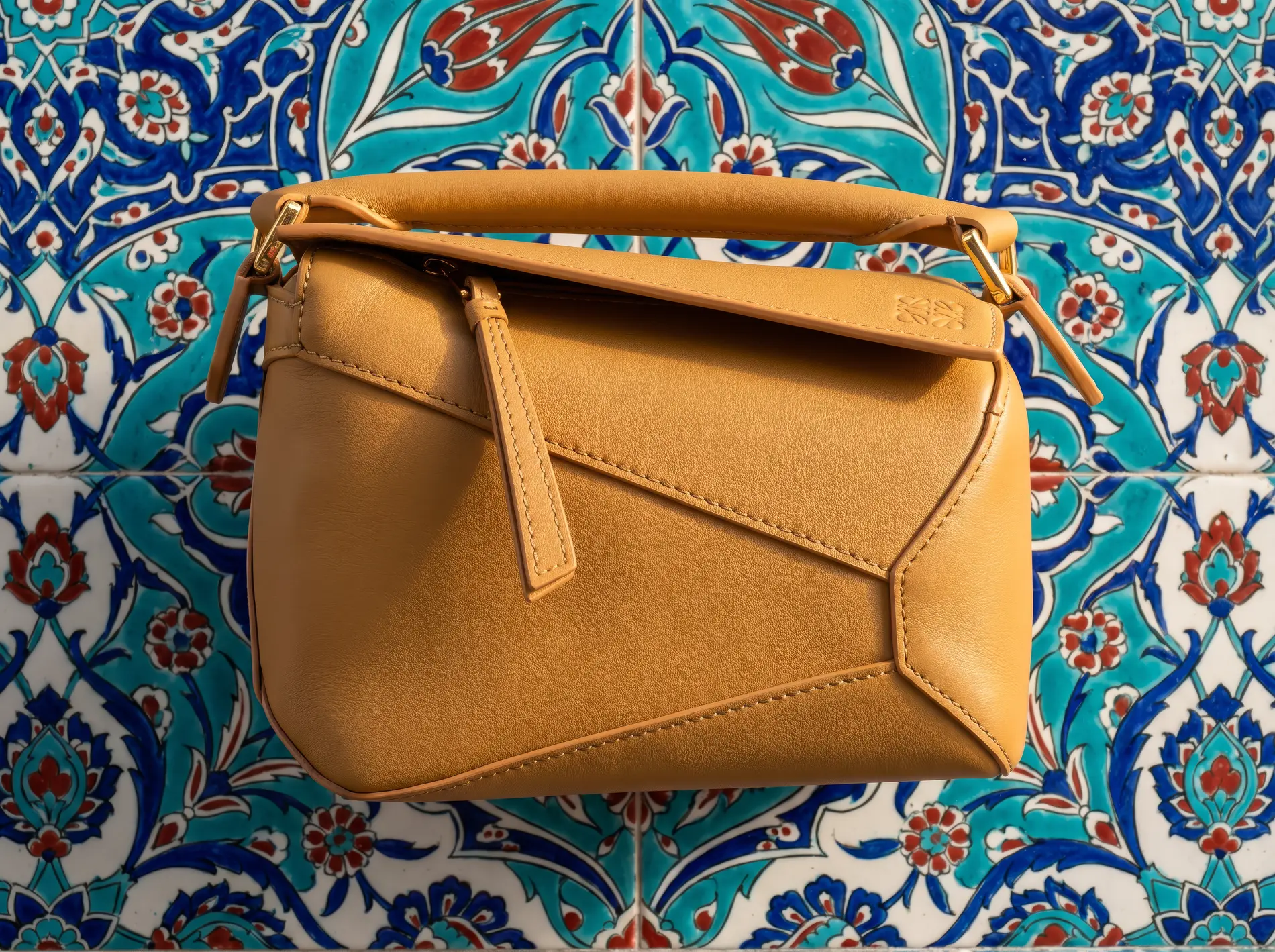 Camel leather bag laid across traditional Istanbul tilework